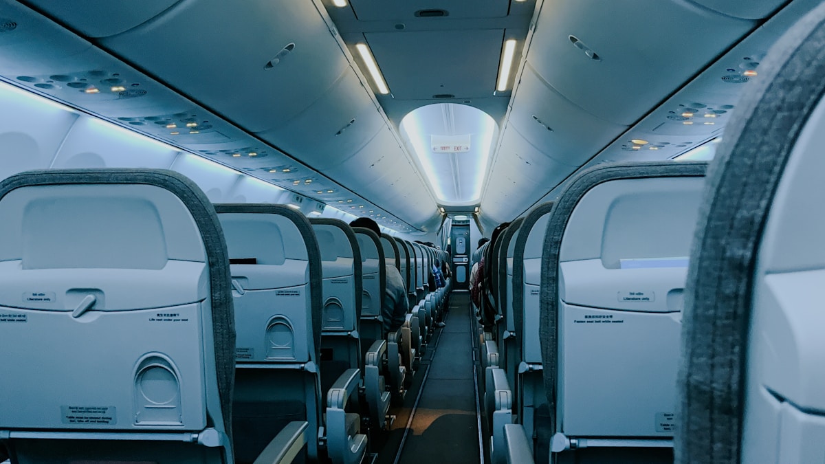 Intérieur d'un avion avec sièges alignés et éclairage bleuté.