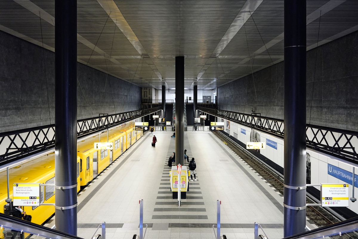 Gare souterraine moderne avec quais, escaliers et signalisation.